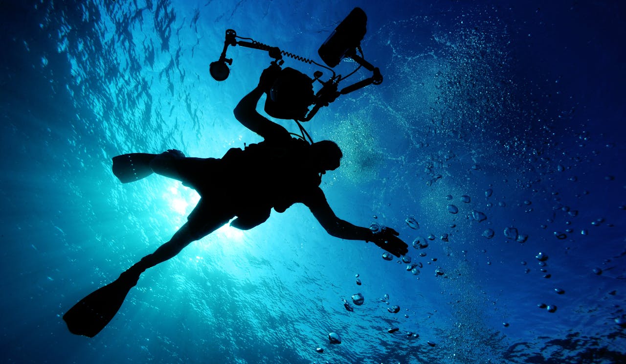 Silhouette of a diver filming underwater, capturing the serene oceanic environment.